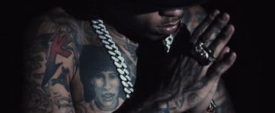 a man with tattoos holding his hands together