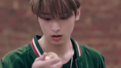 a boy in a green jacket holding a piece of food