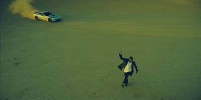 a person standing in the middle of a field next to a car