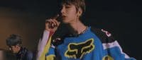 a young man smoking a cigarette while wearing a colorful sweater