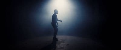 a man standing in a dark room with a light shining on him