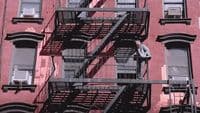 a man standing on a fire escape in front of a building