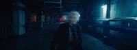 a man with white hair walking down a dark hallway