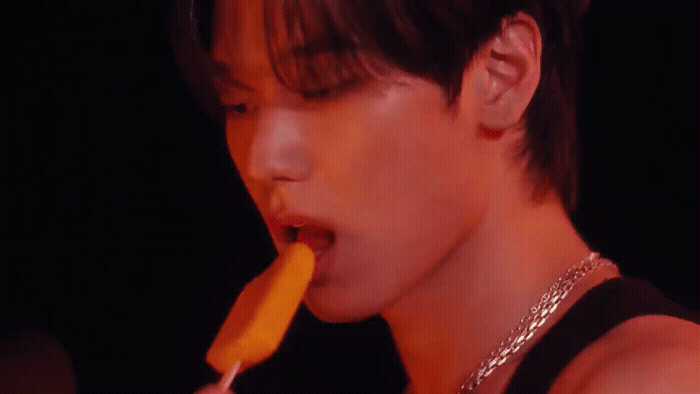 a young man eating a carrot with his tongue out