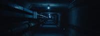 a long dark hallway with benches and lights