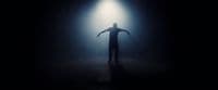 a man standing in the dark with his arms outstretched