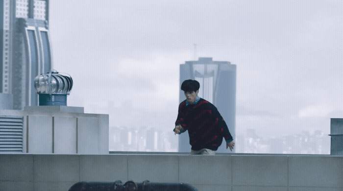 a man standing on top of a roof next to a tall building
