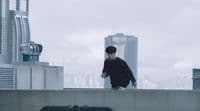 a man standing on top of a roof next to a tall building