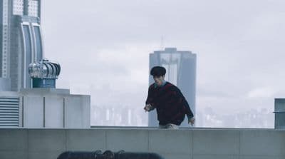 a man standing on top of a roof next to a tall building
