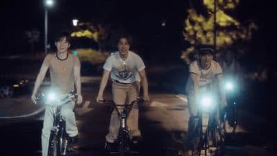 a group of people riding bikes down a street at night