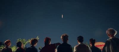 a group of people watching a kite fly in the sky