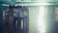 a group of people standing on top of a beach next to the ocean