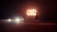 a man walking next to a car at night