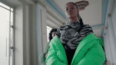 a woman in a green jacket standing in a room