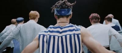 a man with dreadlocks standing in front of a group of people