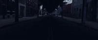 a dark street with a clock on the side of it