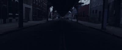 a dark street with a clock on the side of it