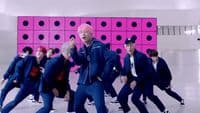 a group of young men dancing in front of a pink wall