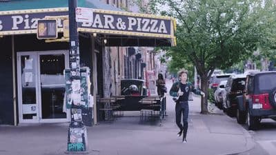 a woman walking down a street next to a restaurant