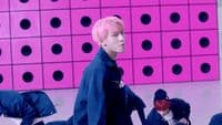 a man with pink hair walking on a runway