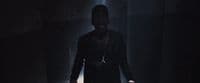 a man standing in a dark room with his hands in his pockets