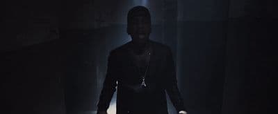 a man standing in a dark room with his hands in his pockets