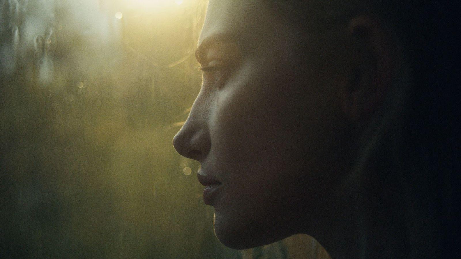 a woman looking out a window at the sun