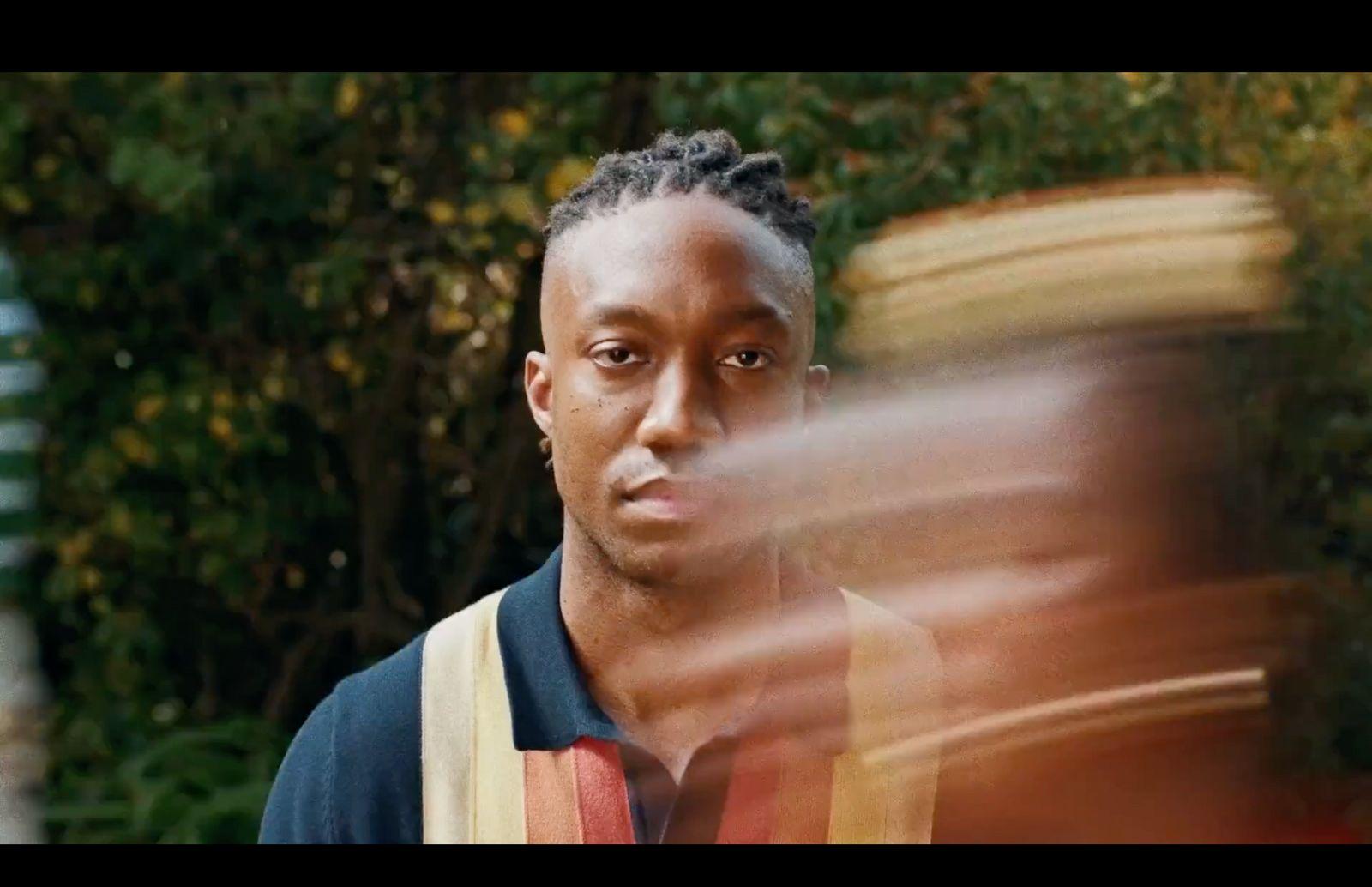 a man with dreadlocks standing in front of a tree