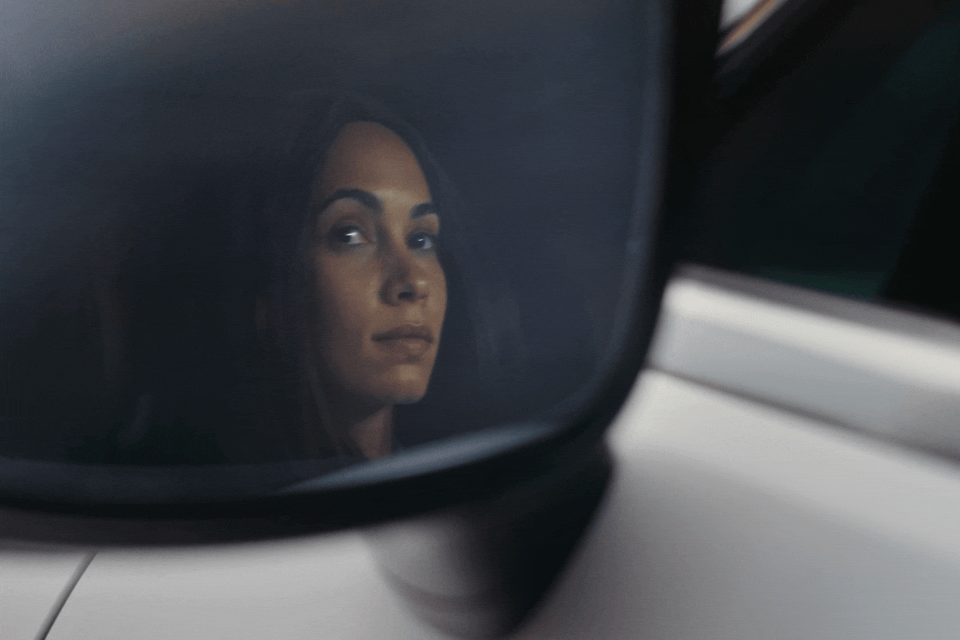 a woman's reflection in the side view mirror of a car