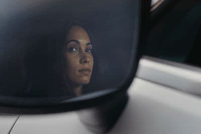 a woman's reflection in the side view mirror of a car