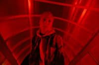a man standing in a red light tunnel