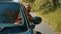 a woman leaning out the window of a car