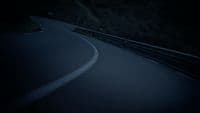 a car driving down a winding road at night