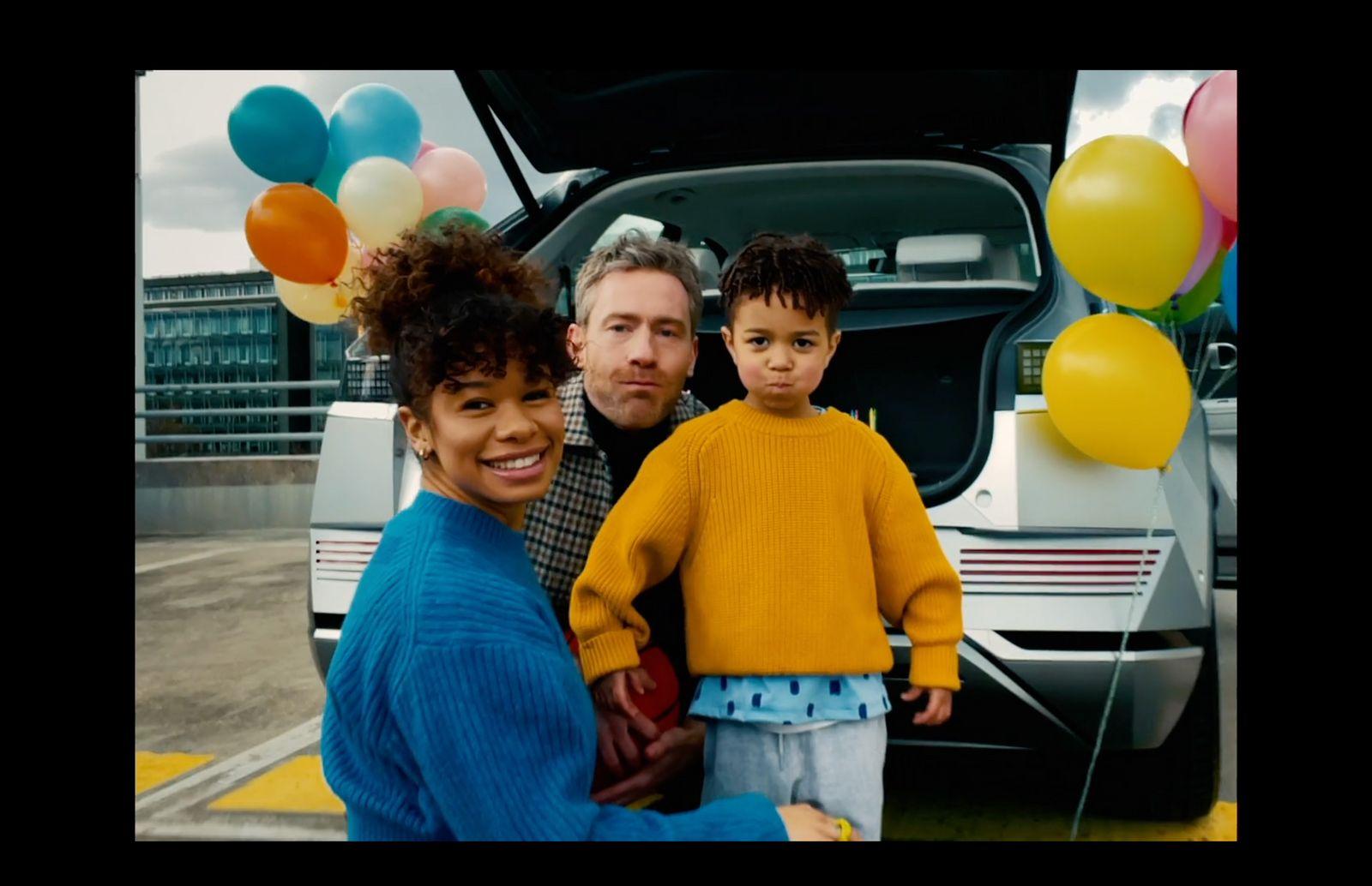 a man and two children standing in front of a car