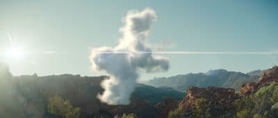 a cloud shaped like a cross on top of a mountain