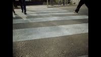 two people walking across a cross walk in the dark