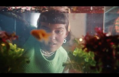 a woman in a green sweater looking at a fish