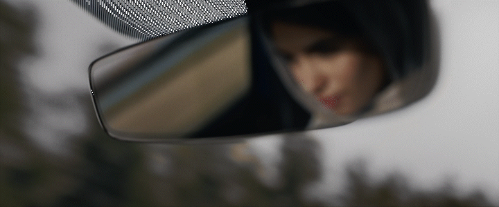 a woman's reflection in the side view mirror of a car
