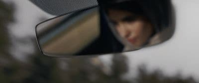 a woman's reflection in the side view mirror of a car