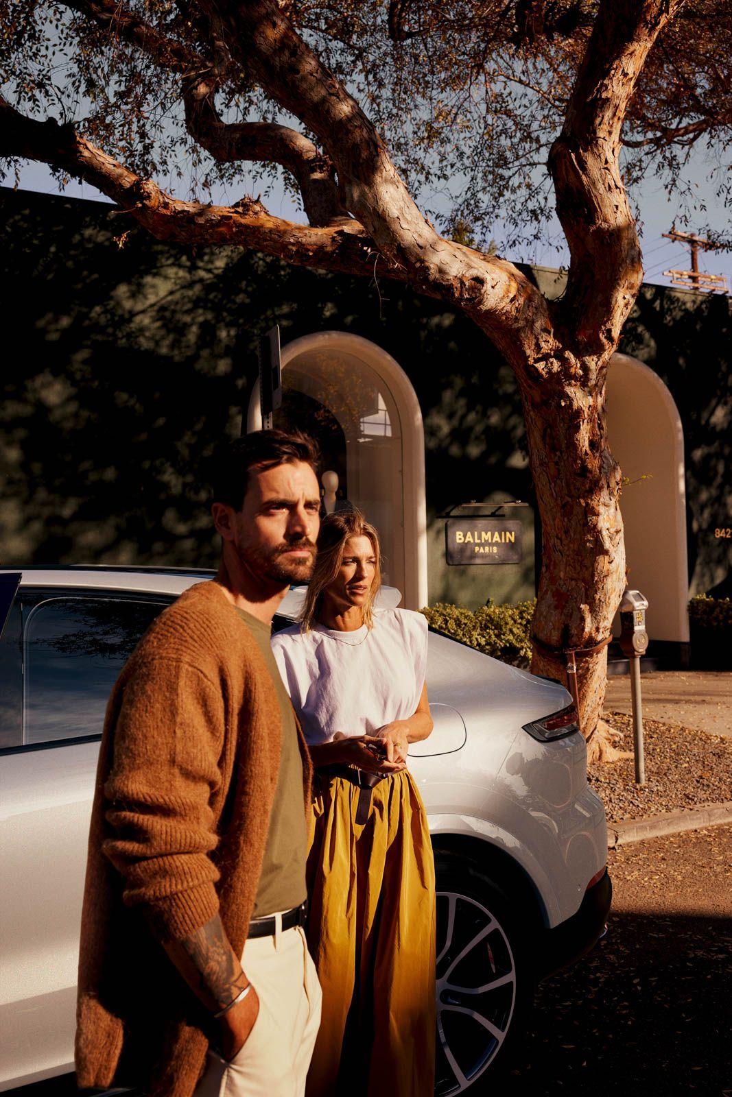 a man and a woman standing next to a white car