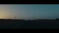 a car driving down a road at sunset