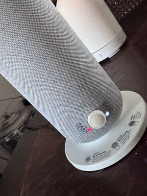 a white speaker sitting on top of a wooden table