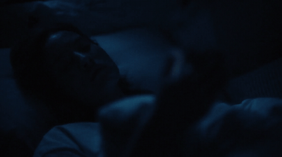 a person sleeping in a dark room with their head on a pillow
