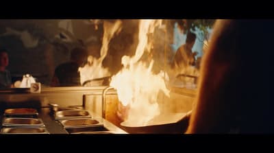 a person standing in front of a fire in a kitchen