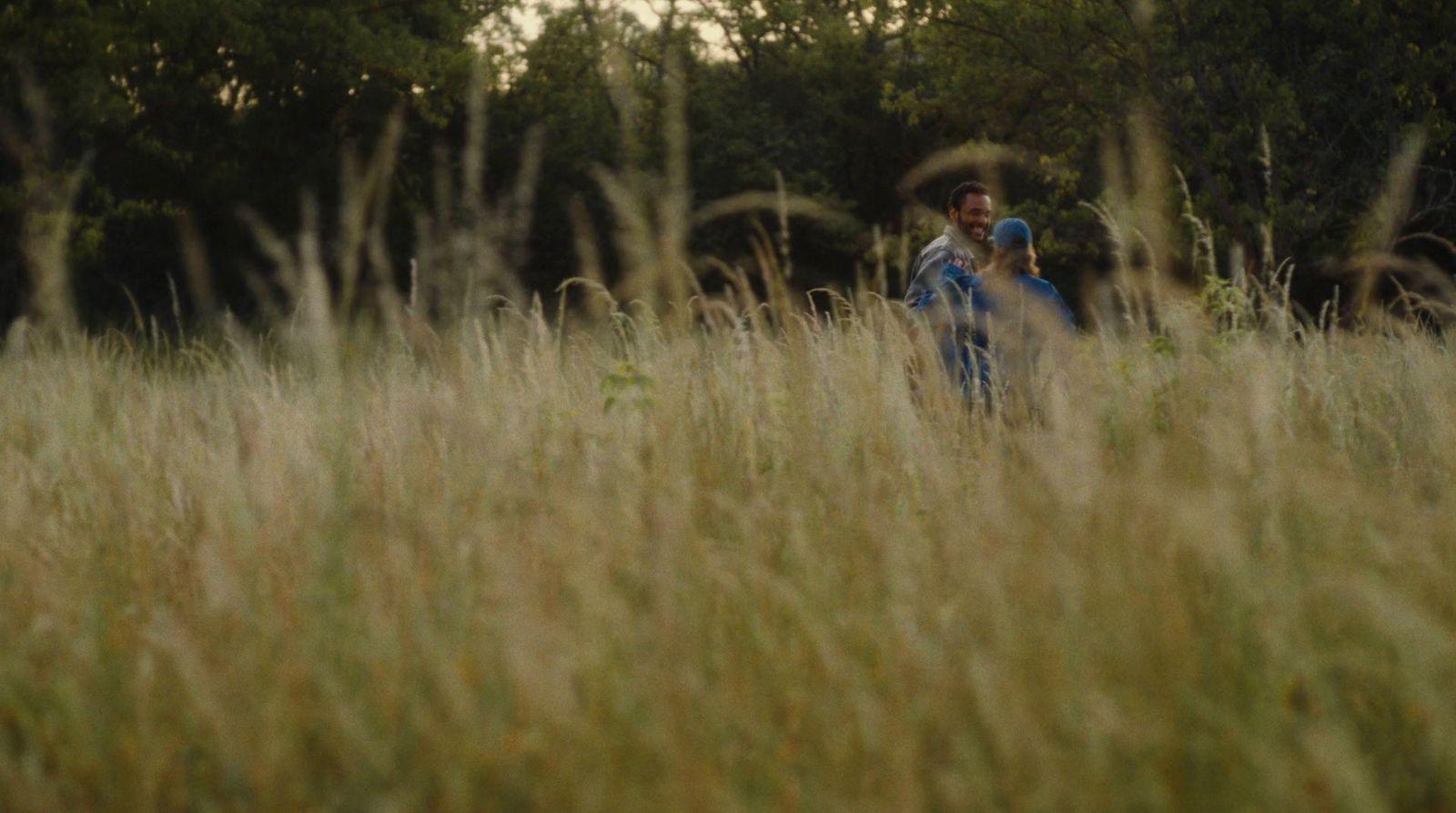 a woman holding a child in a field of tall grass
