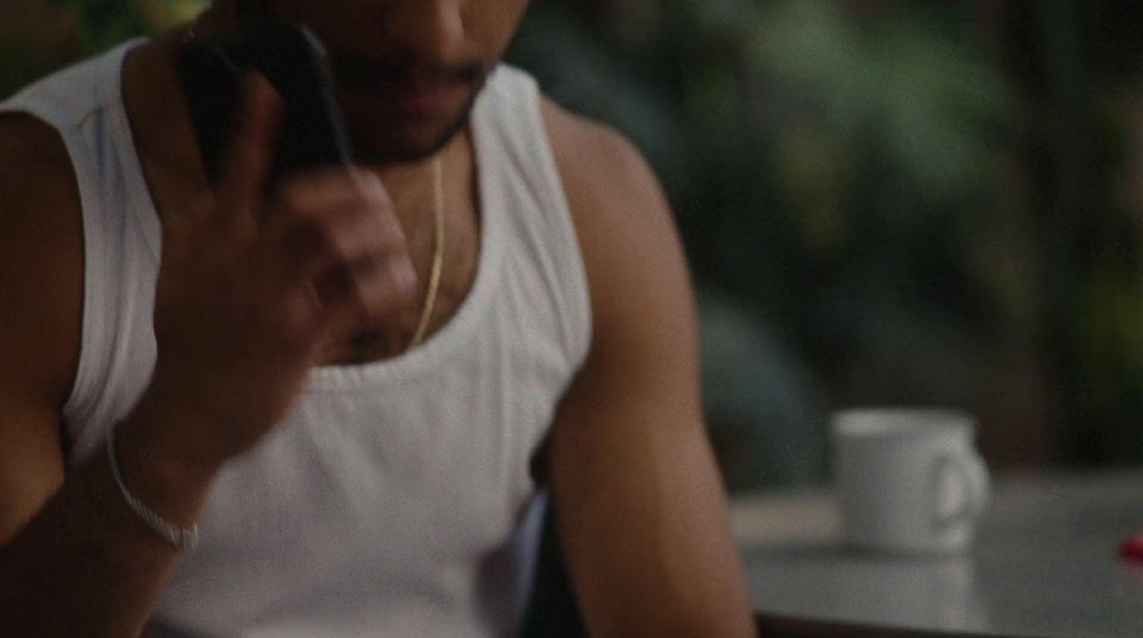 a man in white tank top using a cell phone