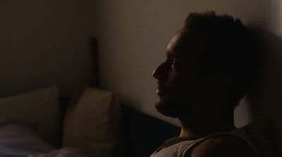 a man is looking out of a window in a dark room