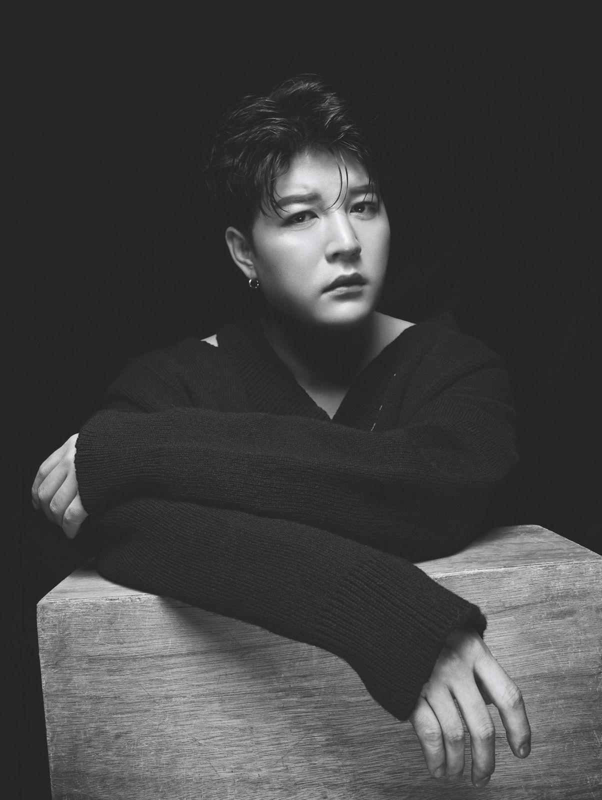 a black and white photo of a person leaning on a table