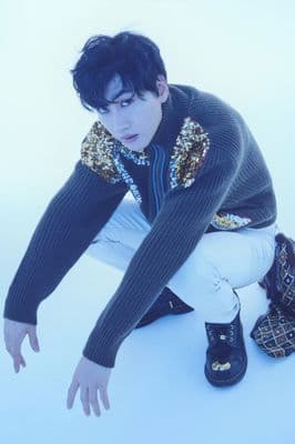 a man in a black sweater and white pants