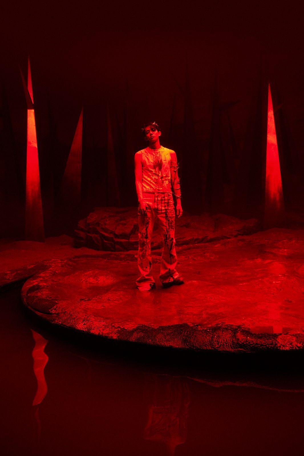 a man standing on a stage with red lights